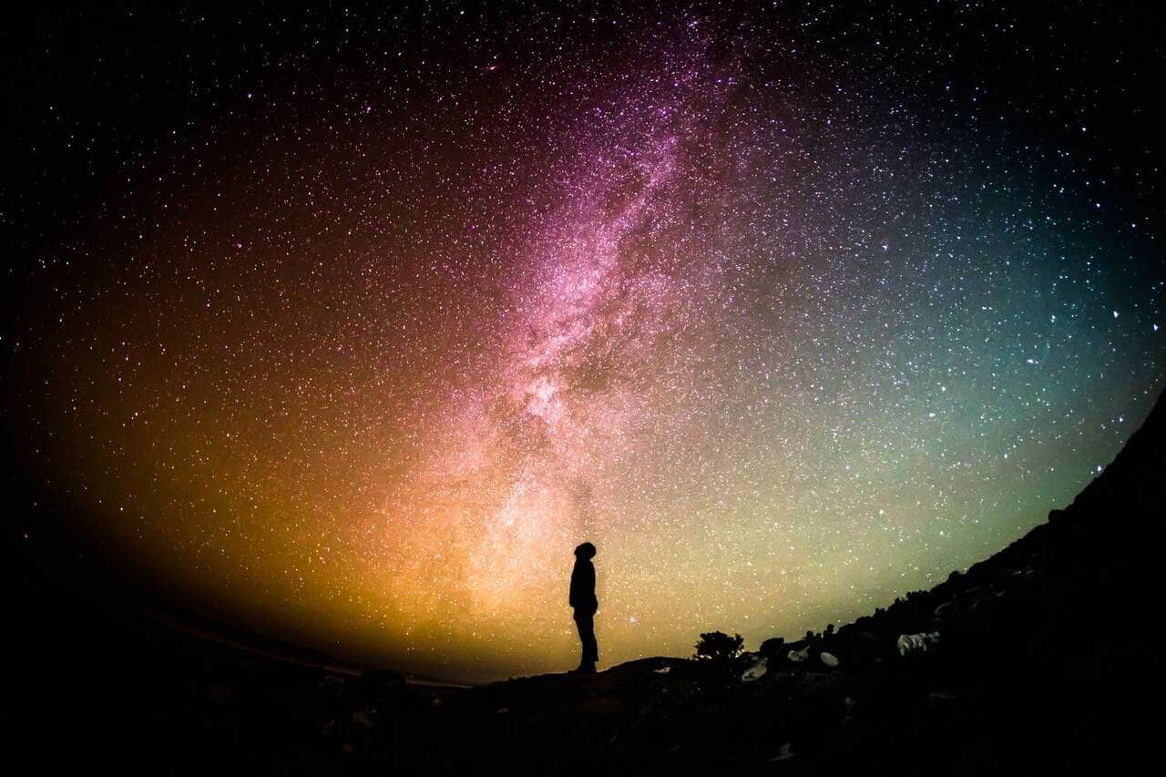 A figure beneath a vast, starlit night sky